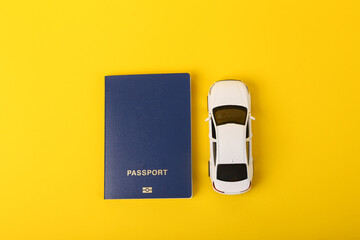 Toy car model with a passport on a yellow background. Travel concept