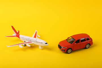 Toy car model with an airplane on a yellow background. Travel concept