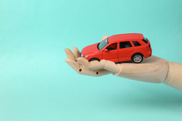 Toy car on the palm of a woman's hand on blue background. Protection, insurance auto concept