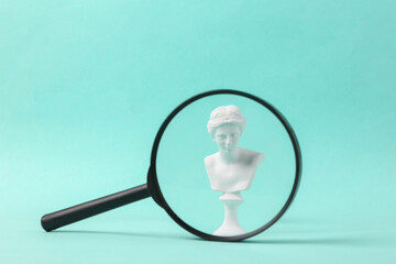 Antique statue of venus through a magnifying glass on a blue background