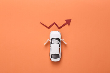 Toy car with growth arrow on coral colored background