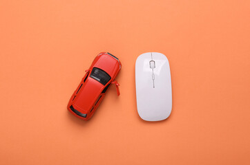 Toy model auto and pc mouse on coral color background. Online car order