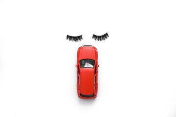 Toy car model with eyelashes on white background. Top view. Minimal composition