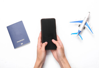 Travel concept. Hand using smartphone on white background with passport and toy airplane