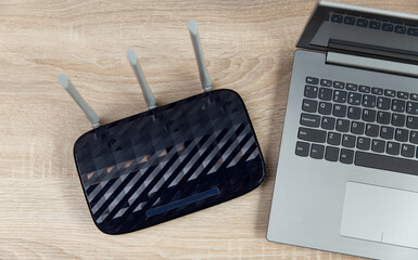 Wi-Fi router and laptop on a wooden table. Top view