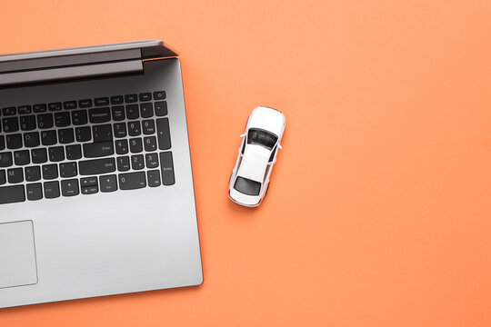 Online Car Search. Laptop With Car On Coral Background. Top View