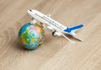 Toy model of a passenger plane with globe on wooden table