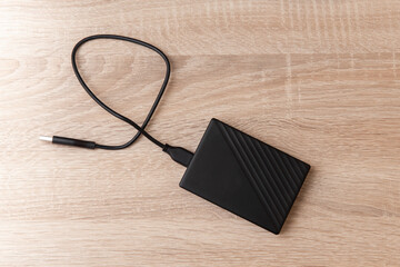 External hard drive with cable on a wooden table