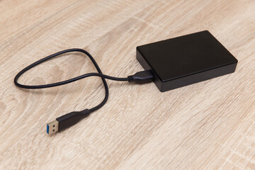 External hard drive with cable on a wooden table