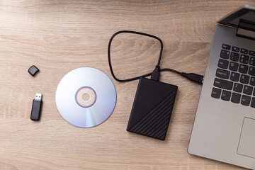 Digital custodians of information. External hard drive, cd and usb flash drive, laptop on a wooden...
