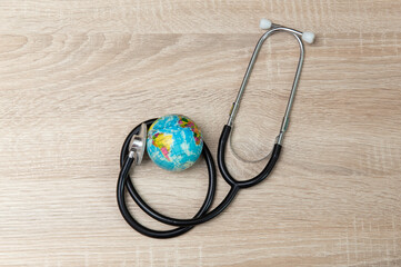 Stethoscope with globe on wooden table