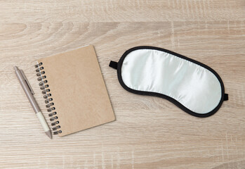 Sleeping mask with notebook on a wooden table