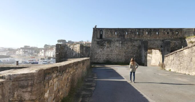 young girl with her camera visiting Ciboure in the Basque Country with the fanmeux fort of Socoa