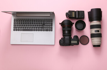 Set of professional photographic equipment (camera with lenses) with laptop on a pink background. Top view. Flat lay