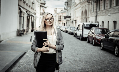 Portrait of confident business woman with folder in hands in urban street