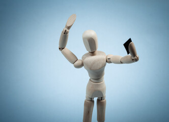 Wooden puppet makes a selfie with a smartphone in hand on blue background