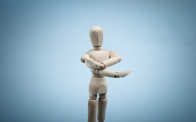 Wooden puppet stretches arms isolated on blue background. Healthy lifestyle, sport concept