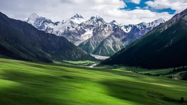 Aerial footage of green grassland and snow mountain natural landscape in Xinjiang, China. 