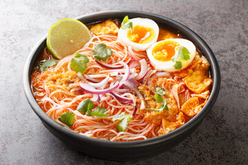 Burmese Mohinga Rice Noodle Fish Soup closeup in the bowl on the table. Horizontal