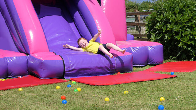 Red headed boy having fun playing on bouncy castle