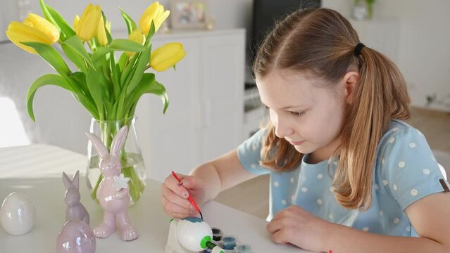4K 60 fps of pretty little girl with pigtails painting easter egs at home