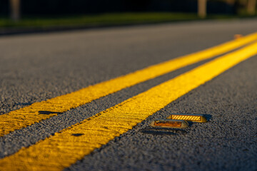 Double yellow road lines reflecting bright sunlight - Powered by Adobe