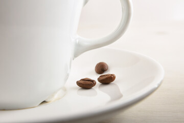 Cup of coffee on plate with beans on white front