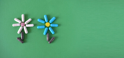 two flowers made from pills and capsules for treatment on a green background