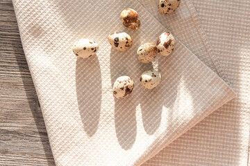 Quail eggs lie on a linen towel on a gray table in the kitchen of the house.