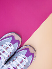Pair of new stylish sneakers on a pastel orange and bright pink background, copy space