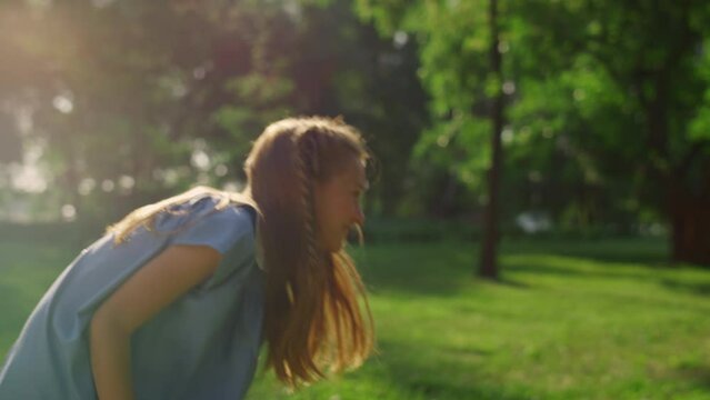 Cute girl picking hit shuttlecock with racket in golden sunlight. Family weekend