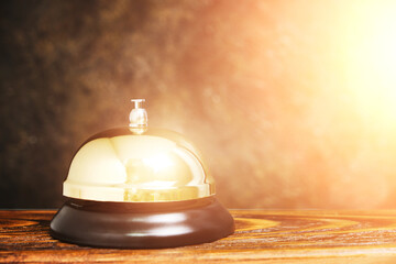 Gilded bell hotel service against background concrete wall with sunlight.Conceptual hotel, travel and recreation.