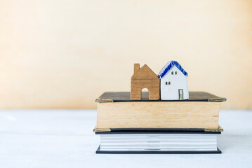 Obraz na płótnie Canvas Two vintage design miniature house on stack of book with space on blurred background, real estate and property study, learning architect, house loan legal