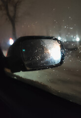 car mirror through glass with drops in the dark