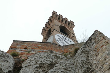 clock tower in Brisighella with mighty brick walls and the clock face at six hours on a hill that dominates the village