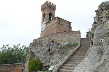 clock tower in Brisighella with mighty brick walls and the clock face at six hours on a hill that dominates the village