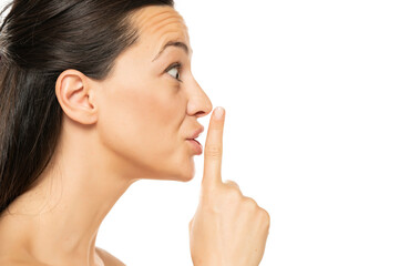 Excited young  woman with a finger on her lips
