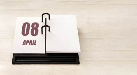 April 8. 8th day of month, calendar date. Stand for desktop calendar on beige wooden background. Concept of day of year, time planner, spring month