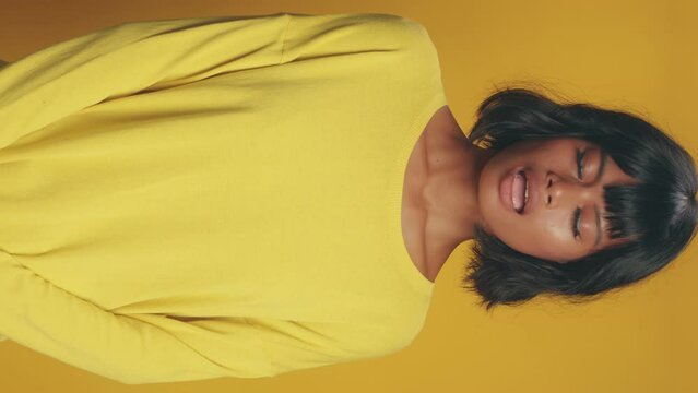 Headshot vertical portrait of modest shy Latin American woman not daring to say or object because of self-doubt and psychological clamps stands in studio on yellow background. Problems socialization