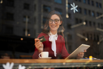 Happy woman using credit card to shopping online with tablet. Beautiful young woman drinking coffee in cafe..