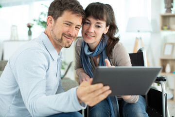 Fototapeta premium woman in wheelchair showing tablet to her partner