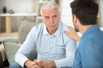 depressed old man while son is helping him