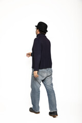 Three-quarter man walks to the left. He is wearing a blue sweater, jeans and a bowler hat.