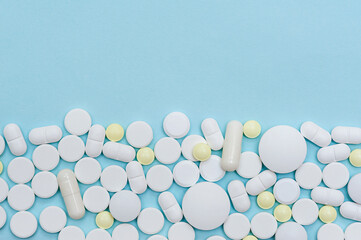 Border of scattered medical pills on a blue background with copy space. - Powered by Adobe