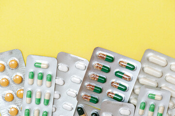 Pharmaceutical drugs antibiotics, colorful antibacterial pills in a blister pack on a yellow background. Top view, flat lay, copy space.