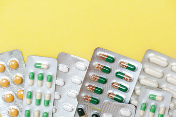 Pharmaceutical drugs antibiotics, colorful antibacterial pills in a blister pack on a yellow...