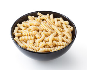 Uncooked fusilli corti bucati pasta in black bowl isolated on white background with clipping path