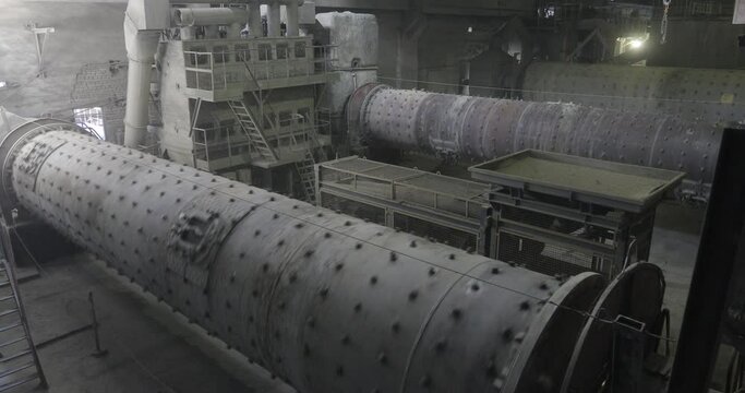 View inside a factory. Tubes is circling. Pipes is turning around. Cement production. Place isn't relevant. Machines is working in the factory. Gray and dirty factory equipment. Gray or sand are using