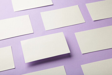 Mockup of horizontal business cards stacks arranged in rows at purple textured paper background.