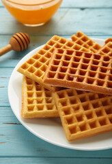 Belgian waffles on blue background. Belgian waffles with honey and milk. Freshly baked Belgian waffles.